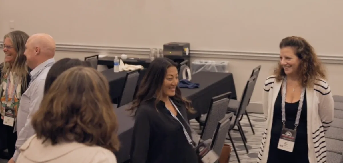 Two workshop participants laughing together as they talk during a session.